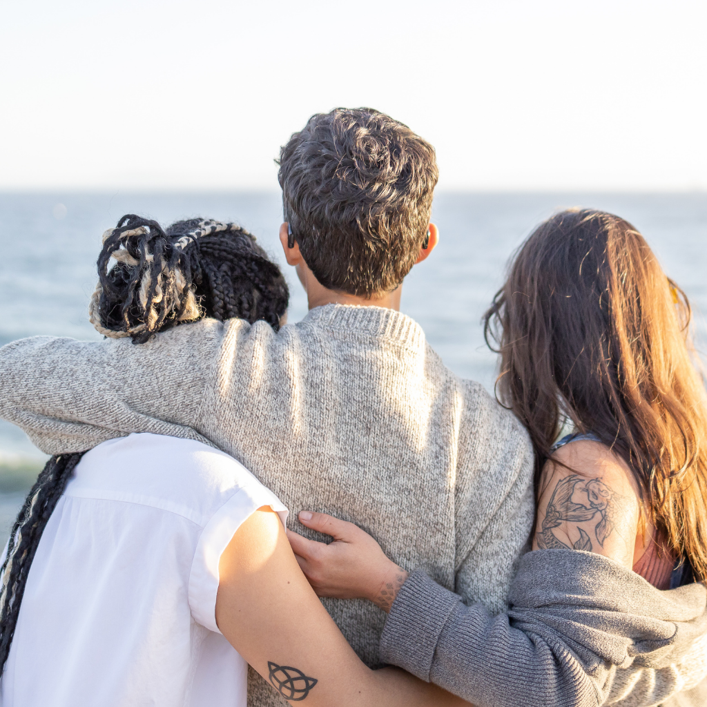 Kind Cup team overlooking the ocean and hugging in comfortable embrace