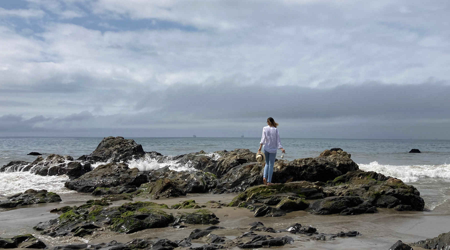 Lady standing in the ocean rocks